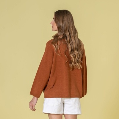 Mulher de costas com camisola castanha e calções brancos