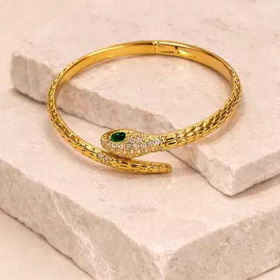 Pulseira dourada com design de cobra decorada com pedras brilhantes e olhos verdes