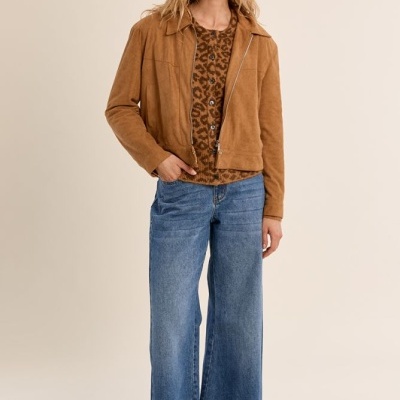 Mulher com casaco castanho, blusa animal print, calças jeans largas e sapatos castanhos