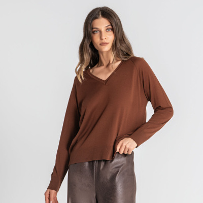 Mulher com camisola castanha de malha e calças castanho escuro