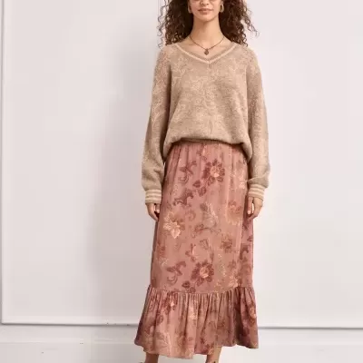 Mulher com camisola bege e saia floral rosa