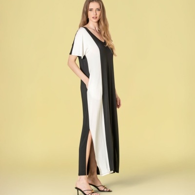 Vestido maxi bicolor preto e branco com decote e fenda e sandálias pretas.