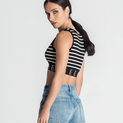 Mulher de lado a usar top cropped às riscas pretas e brancas e jeans azuis claros