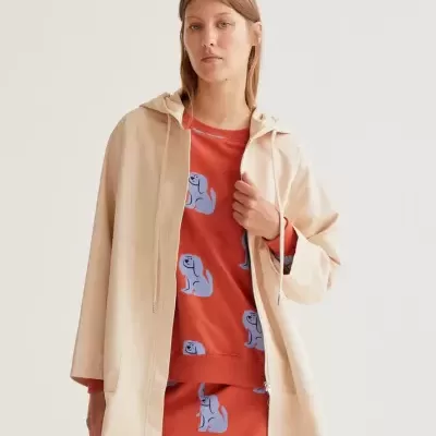 Mulher com casaco bege e vestido vermelho com padrão de cães azuis