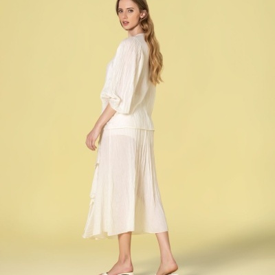 Vestido creme amassado com manga comprida e saia midi fluida, usado com sandálias creme de salto médio