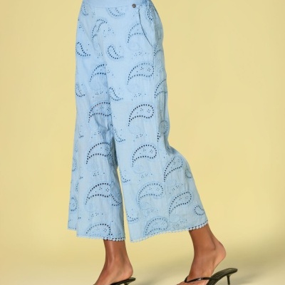 Calças azuis bordadas com padrão vazado e sandálias pretas com salto fino