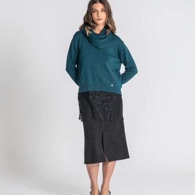 Mulher veste camisola azul petróleo e saia preta com renda
