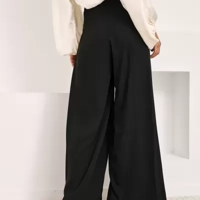 Calças largas pretas e blusa creme vista de costas