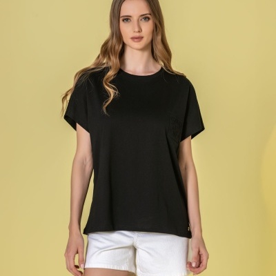 Mulher vestindo t-shirt preta de manga curta com bolso e calções brancos em fundo amarelo