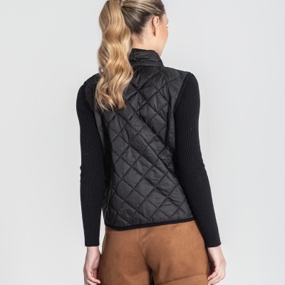 Mulher de costas com colete preto acolchoado e calções castanhos