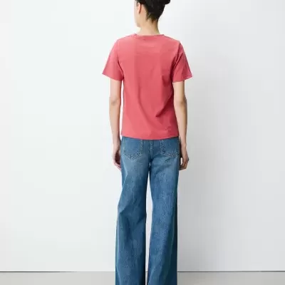 Mulher de costas com t-shirt rosa e calças de ganga azuis largas