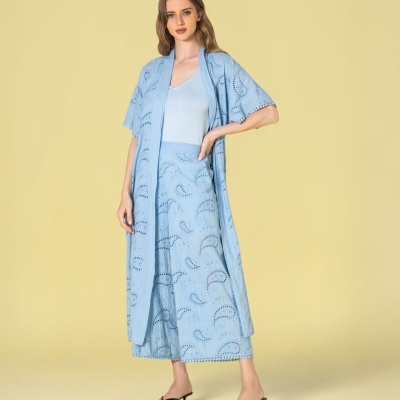 Modelo veste conjunto azul claro com padrão recortado e sandálias pretas.