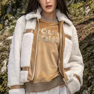 Mulher com casaco de pêlo branco e camisola camel com texto 'YOUR SOUL' em ambiente exterior com rochas