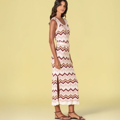 Mulher com vestido longo malha padrão zig-zag e cinto rosa com fenda lateral