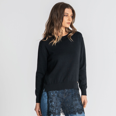 Mulher com camisola preta e jeans azuis com renda preta.