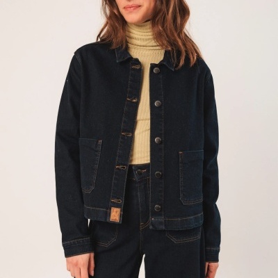 Casaco de ganga azul escuro com botões e bolsos, mulher com camisa bege.