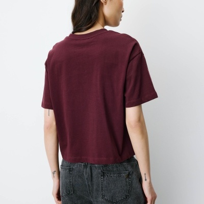 Pessoa de costas com t-shirt bordeaux e calças de ganga pretas
