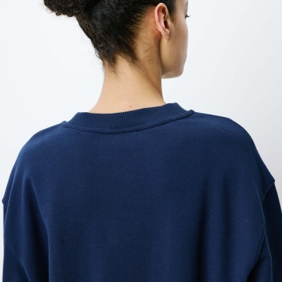 Pessoa de costas com camisola azul escura e cabelo apanhado em coque