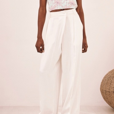 Modelo com calças brancas compridas e top cropped floral rosa
