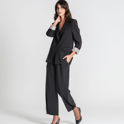 Conjunto de fato feminino preto com blazer e calças largas, sapatos pretos de salto, fundo branco