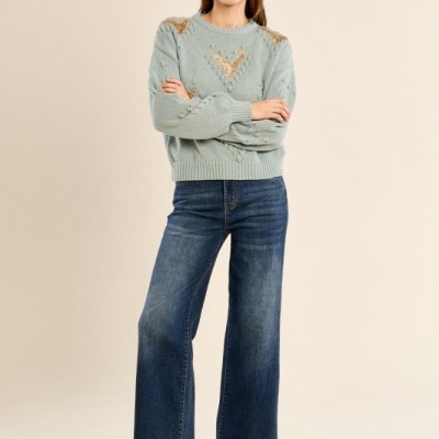 Mulher com camisola azul clara, jeans flare e botins castanhos