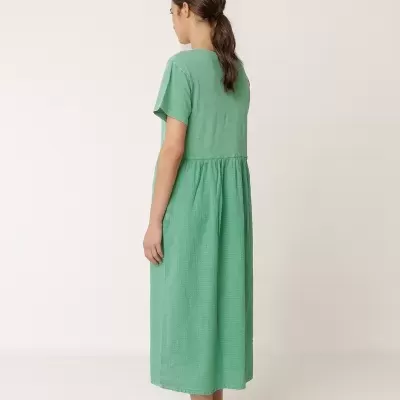 Mulher de costas com vestido verde midi de manga curta e sandálias castanhas