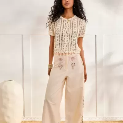 Conjunto feminino creme de top de malha e calças largas bordadas em ambiente interior