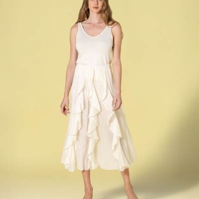 Mulher com blusa branca sem mangas e saia branca midi com babados