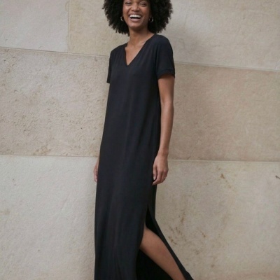 Mulher a vestir vestido comprido preto de manga curta com decote em V e racha lateral