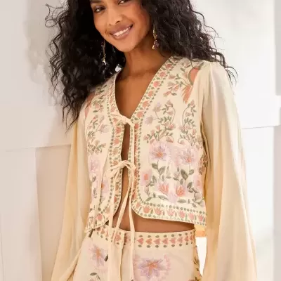 Conjunto de roupa bordado com camisa e calças bege com flores em tons pastel