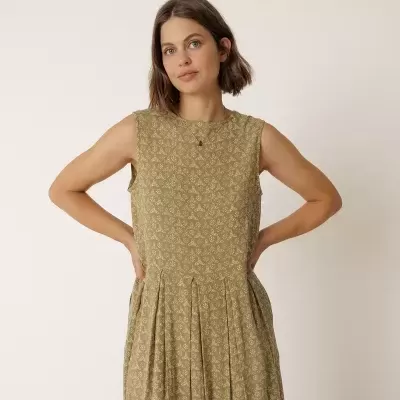 Vestido verde com padrão branco, sem mangas, em modelo feminino com fundo branco