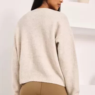 Mulher com camisola bege clara e calças castanhas vista de costas