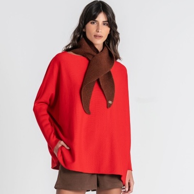 Mulher com camisola vermelha, cachecol castanho e calções castanhos