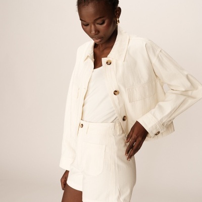 Mulher a usar casaco branco, camisa branca e calções brancos