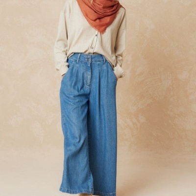 Mulher com roupa casual com calças largas de ganga e lenço cor de ferrugem