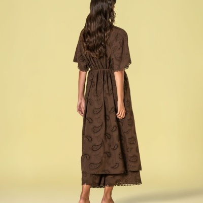 Modelo de vestido comprido castanho com padrão bordado e sandálias castanhas
