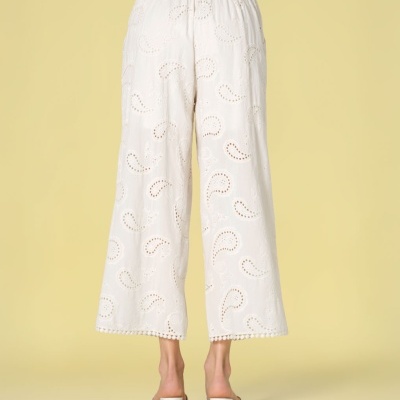 Calças brancas femininas com bordado vazado e barra com pequenas bolas.