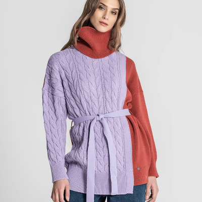 Mulher de camisola malha lilás e castanha com cinto e calças azuis