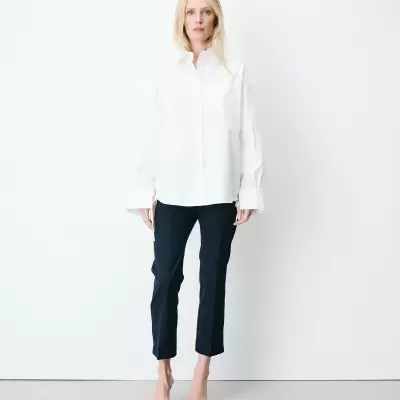 Mulher veste blusa branca de manga comprida e calças pretas risca-de-giz
