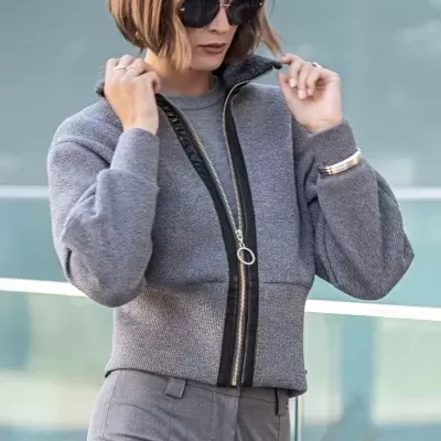 Mulher com casaco cinzento de lã e óculos escuros num ambiente urbano.