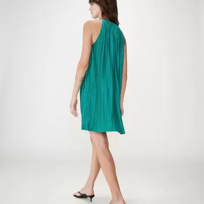 Vestido verde plissado visto de costas com sandálias pretas em fundo branco.