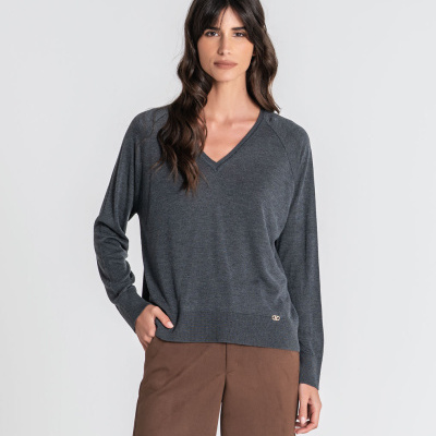 Mulher com camisola cinza escura de malha e calças castanhas