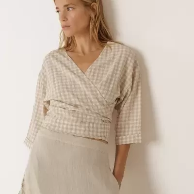 Mulher com blusa xadrez bege e branca e saia bege clara