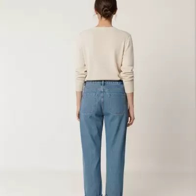 Pessoa de costas com camisola bege e calças de ganga azul