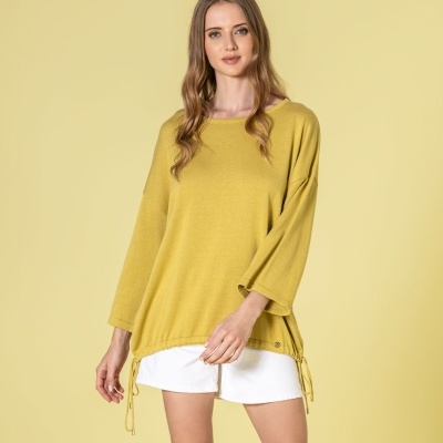 Mulher com camisola amarela clara e calções brancos em fundo amarelo