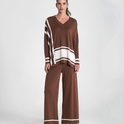 Conjunto de malha castanha com riscas brancas, top e calças largas, com sapatilhas castanhas.