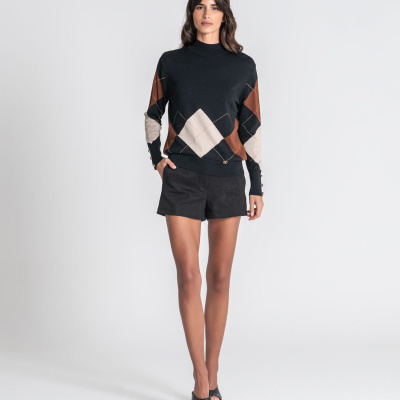 Mulher com camisola de malha argyle e calções pretos.