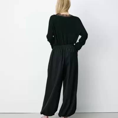 Mulher de costas com roupa preta e sapatos pretos em fundo branco