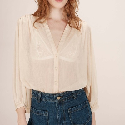 Blusa transparente bege com botões e calças de ganga azul escuro