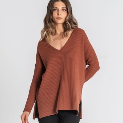 Mulher com camisola castanha de malha canelada com decote em V e calças pretas.